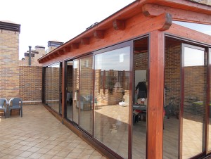 terraza cerrada con puertas de cristal sobre estructura de madera como un porche